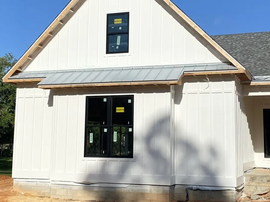 White board-and-batten house with new roof framing